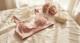 A soft flat lay of a wire-free blush bralette on ivory linen surrounded by dried flowers and a smooth stone, bathed in warm diffused light.